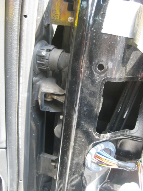 1993 Ford Probe - A close-up view reveals the internal components of a car door, including the hinge mechanism and a bundle of colorful wires.