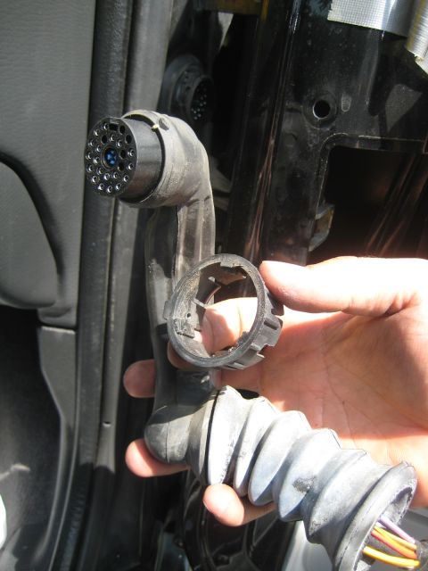 1993 Ford Probe - Close-up of a car's electrical connector and its locking mechanism being held.