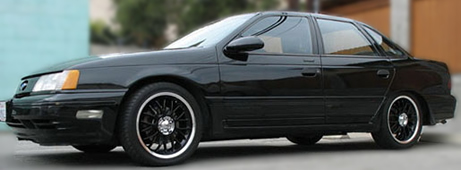 1993 Ford Taurus - A black 1993 Ford Taurus sedan is shown from the front three-quarter angle.
