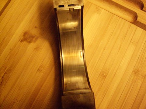 1972 Ford Ranchero - A worn engine bearing is shown against a wooden background, indicating potential mechanical issues.