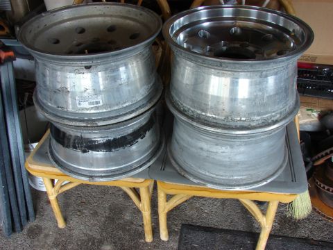 1985 Ford F-150 - A collection of four aluminum wheels are stacked and displayed on a small table.