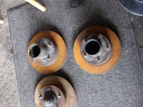 1985 Ford F-150 - Three brake rotors and hubs are shown, likely for a truck or older vehicle, resting on a textured mat.