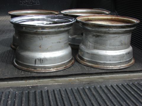 1985 Ford F-150 - Aluminum rims with visible wear and tear are stored in the bed of a pickup truck.
