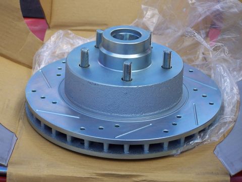 1973 Ford Ranchero - A new cross-drilled and slotted front brake rotor with an integral five-lug hub, still sitting in its plastic-lined cardboard box. The zinc…
