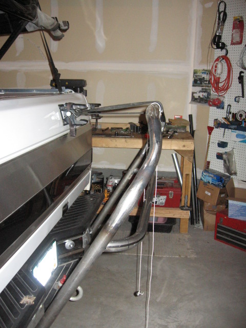 1995 Ford Bronco - A custom roll cage is attached to the rear of a white pickup truck in a garage.