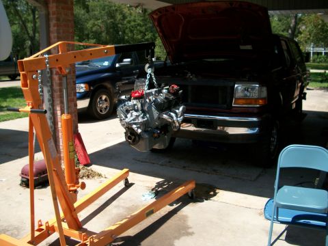 1996 Ford Bronco - An engine is suspended by a hoist, ready for removal or installation in a vehicle.