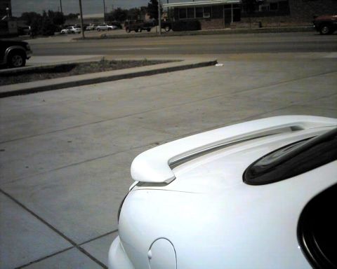 1990 Ford Taurus - Rear view of a white 1990 Ford Taurus, a prominent spoiler and a visible 'SUPERMOTORS' watermark.