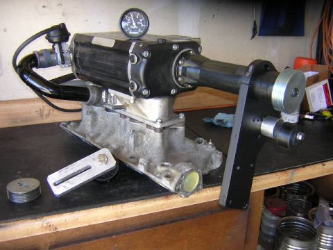 1993 Ford F-150 - A supercharger assembly is shown on a workbench, complete with a boost gauge and intake manifold.