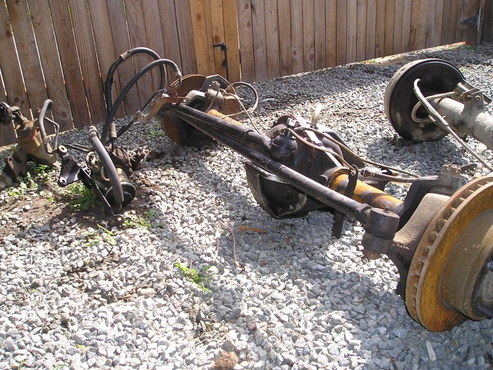 Front and rear axle assemblies with brake rotors and hydraulic lines
