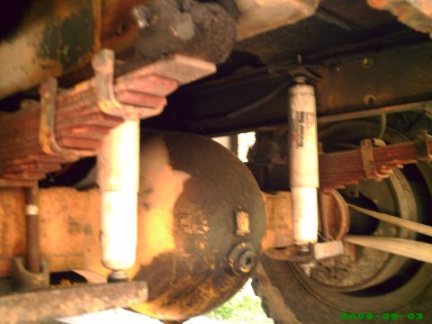 1978 Ford Bronco - The underside of a vehicle displays its suspension components, including leaf springs and shock absorbers.