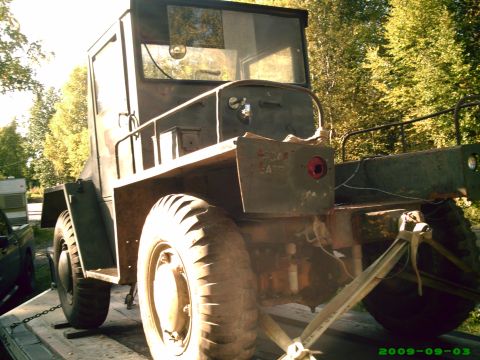 1978 Ford Bronco - This weathered military truck is secured to a trailer, showing its large wheels and utilitarian design.