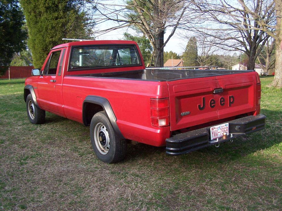 1991 Jeep Comanche pickup truck, rear view. Red paint, black fender flares, black bumper. License plate YVV-7968