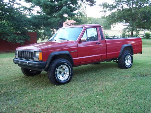1991 Jeep Comanche - A red 1991 Jeep Comanche pickup truck is parked on a grassy lawn.