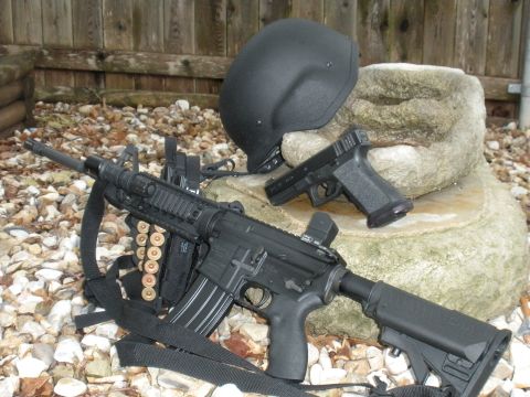 1996 Ford Bronco - An assault rifle, handgun, and helmet are displayed on a rocky surface with a wooden fence in the background.