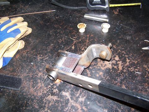 1991 Jeep Comanche - A close-up view of a welded metal bracket and associated parts on a cluttered workbench.