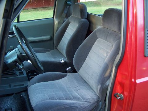 1991 Jeep Comanche - The interior of a red truck shows the front seats, steering wheel, and gear shifter.