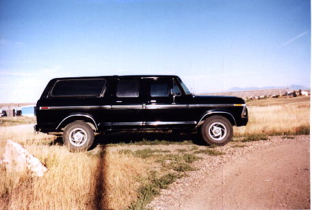 1979 Ford C-250 (Centurion Conversions) - This black SUV is parked outdoors on a sunny day with a dry, grassy landscape.