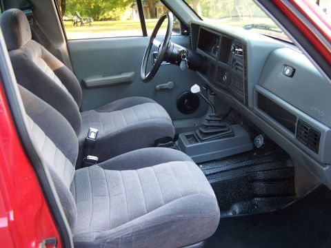 1991 Jeep Comanche - The interior of a Jeep Comanche features cloth seats and a manual transmission shifter.