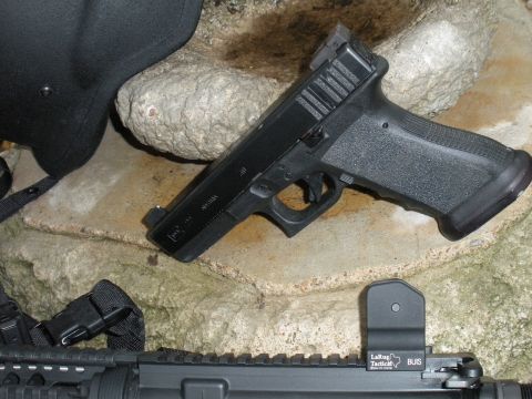 1996 Ford Bronco - A handgun and rifle components are displayed on a rocky surface, with visible branding on-screen text.