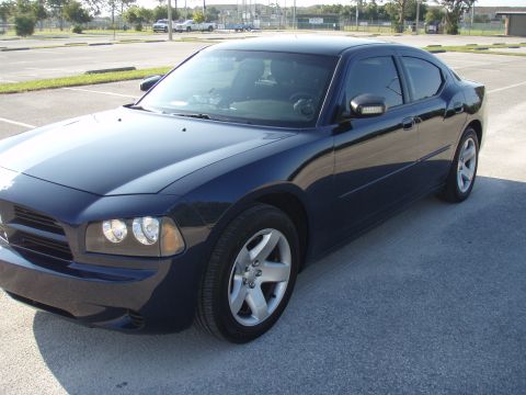 2006 Dodge Charger - A dark blue sedan is parked in an asphalt lot with trees and a fence in the background.