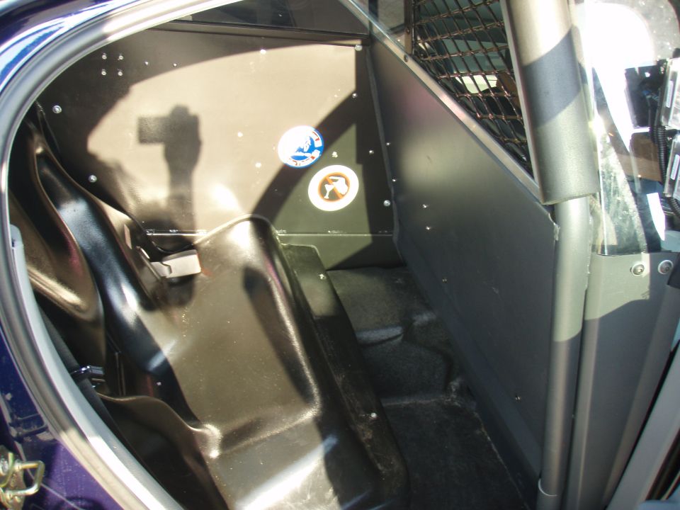 Back seat area of a vehicle with a partition and cage, likely a police car or transport vehicle