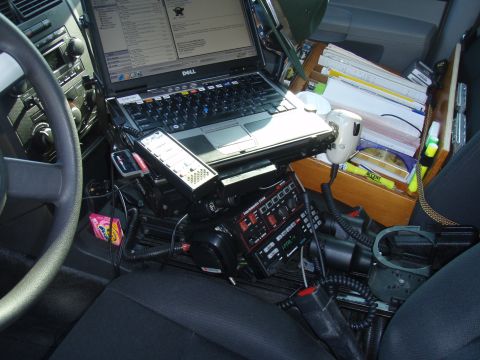 2006 Dodge Charger - The interior of a police vehicle is equipped with a laptop, radio, and various communication devices.