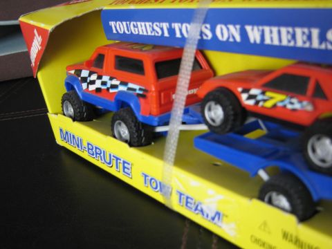 1986 Ford Bronco - A toy truck and trailer set is displayed in its packaging, with text indicating 'TOUGHEST TOYS ON WHEELS'.