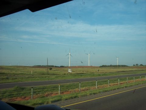 1960 Ford Falcon - View of wind turbines across a field from a moving vehicle, with a highway visible.