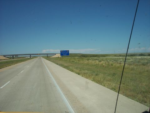 1960 Ford Falcon - A view from a vehicle traveling on a highway through a rural landscape with a bridge and a New Mexico state sign.