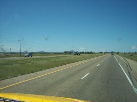 1960 Ford Falcon - Driving down a highway with a clear blue sky and grassy fields on either side.