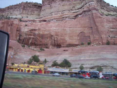 1960 Ford Falcon - A view of roadside buildings and vehicles against a large cliff face.
