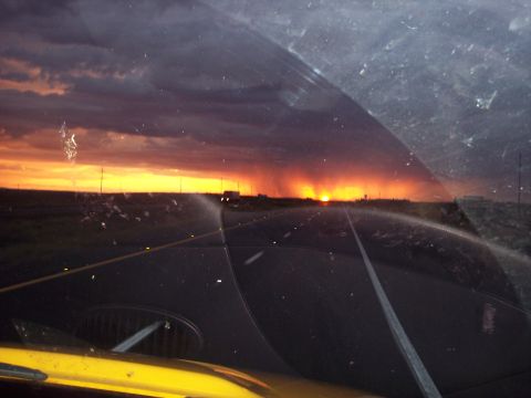 1960 Ford Falcon - Driving on a highway towards a dramatic sunset, with a storm visible on the horizon.