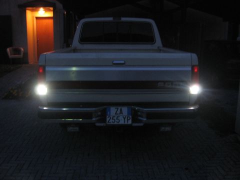 1990 Ford F-150 - The rear of a 1990 Ford F-150 pickup truck is shown at night with its reverse lights illuminated.