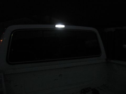 1990 Ford F-150 - The top brake light on a truck is illuminated at night.