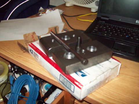 1989 Ford F-150 - A metal jig, likely for automotive work, is placed on a shipping box next to a laptop.