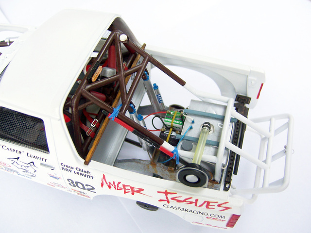 Model truck interior with white roll cage, brown roll bars, fuel cell, and "Anger Issues" text