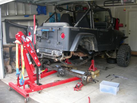 1991 Jeep Wrangler - A Jeep Wrangler is undergoing maintenance in a garage, with its rear axle detached and supported by an engine hoist.
