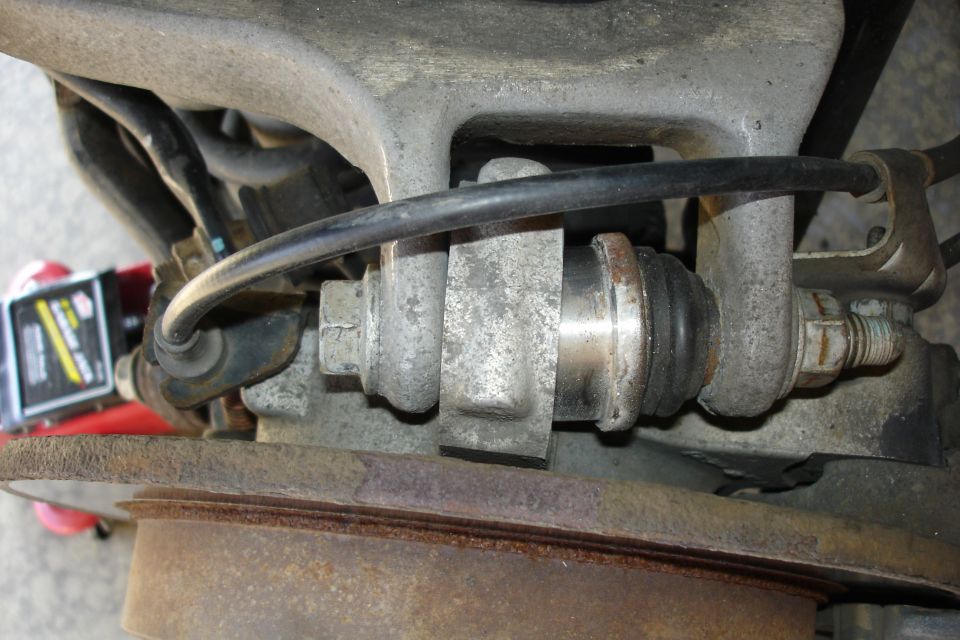 Close-up of automotive ball joint, steering knuckle and rusty brake rotor