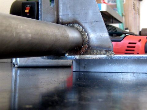 1996 Ford Bronco - Close-up view of a welded metal bracket and pipe, with a power tool visible in the background.