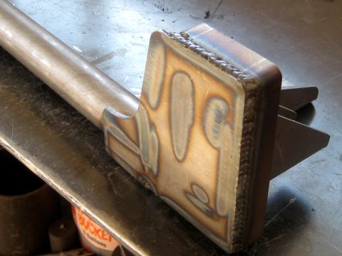 1996 Ford Bronco - A custom-fabricated metal component with distinct weld marks is shown on a workbench.