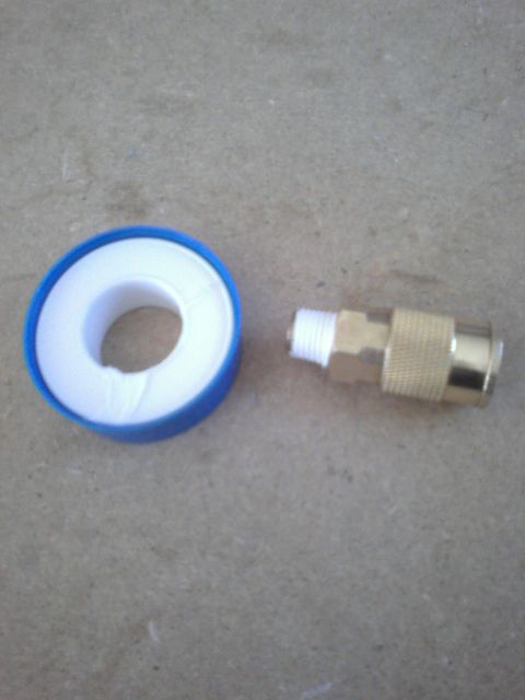 1991 Ford Bronco - A roll of Teflon tape sits next to a brass air fitting on a concrete surface.