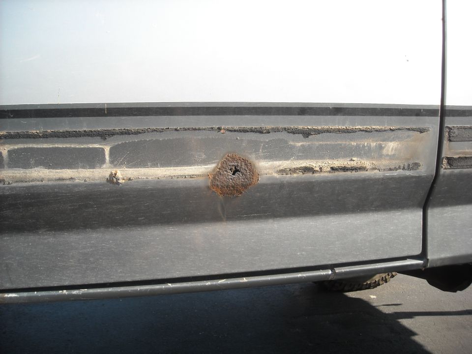 Rust hole on dark gray side panel trim