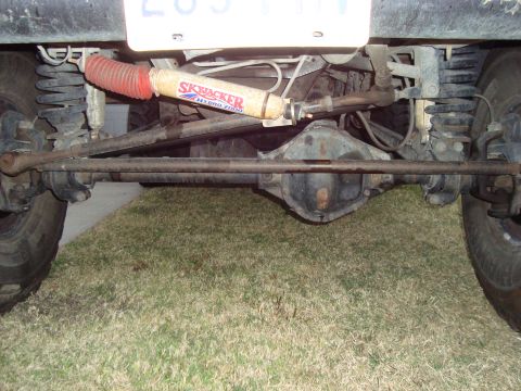 1995 Ford Bronco - The rear axle and suspension components of a vehicle are visible, including a shock absorber and steering linkage.