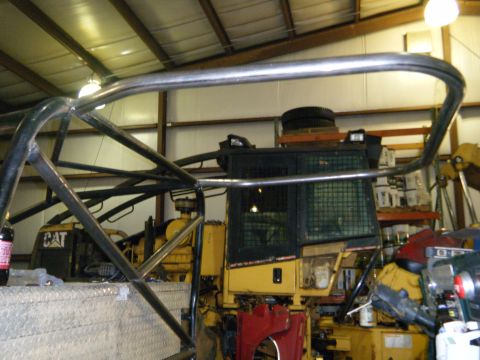 1978 Ford Bronco - A yellow construction vehicle is partially obscured by a metal roll cage inside a workshop.