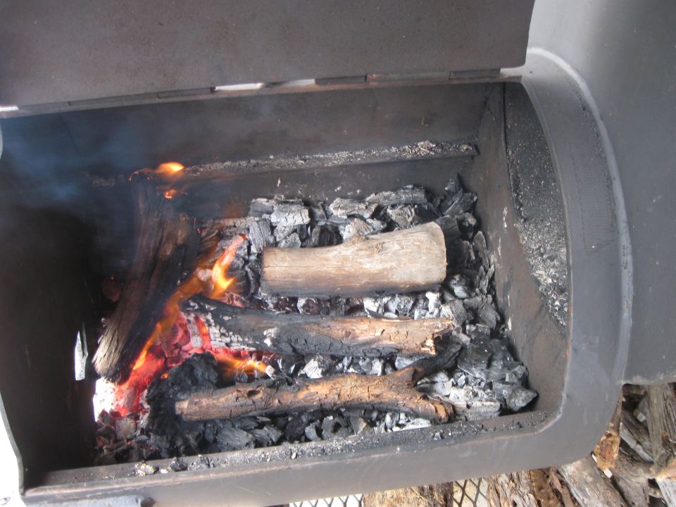 fire burning in a smoker with logs and charcoal