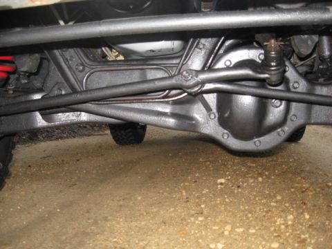 1990 Ford Bronco - Close-up of a vehicle's undercarriage, focusing on the rear axle and steering linkage.