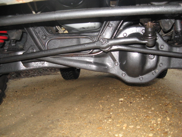 Undercarriage view of a vehicle's rear axle and suspension components, with a tire visible