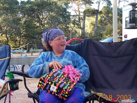 1987 Ford Supercrewzer - A young person sits in a camping chair, unwrapping a birthday present outdoors.