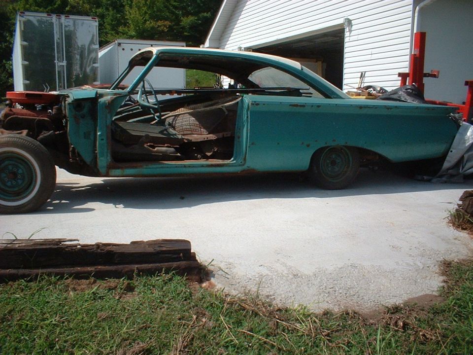 Turquoise 1960 Ford Starliner project shell in side view, missing doors and front sheet metal, in a driveway.
