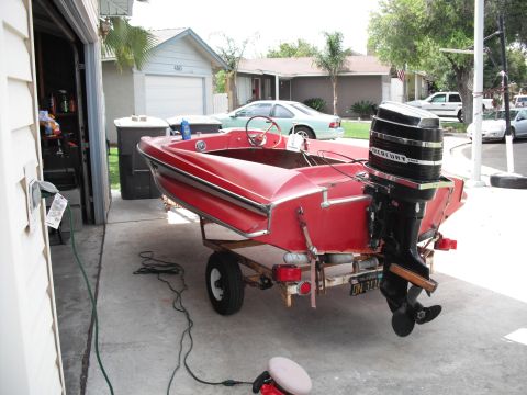 1991 Ford Bronco - A red boat with a Mercury outboard motor is parked on a trailer in a driveway.